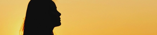 Silhouette of a woman looking to the side in front of a yellow background